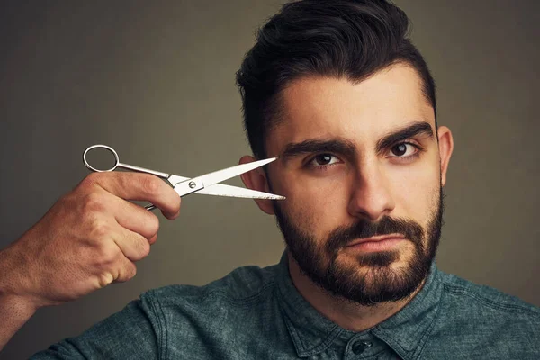 stock image This scissor can go anywhere except on my beard. a handsome young man holding scissors against his head