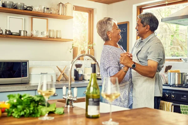 Love starts in the kitchen. a happy mature couple dancing together while cooking in the kitchen at home