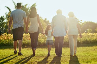 Aile sevgisi için bir araya gelin. Bir ailenin parkta yürüyüş yaparken çekilmiş dikiz görüntüsü.