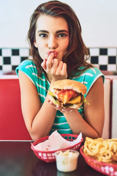 stock image Perfection. Cropped portrait of an attractive young woman enjoying a burger in a retro diner