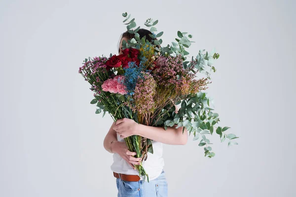 stock image Do you suppose shes a wildflower. Studio shot of an unrecognizable woman covering her face with flowers against a grey background