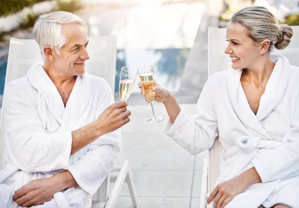 Living it up on this lovely day. a cheerful middle aged couple having a celebratory toast with champagne outside during the day