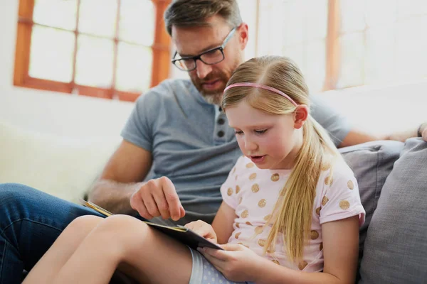 一起阅读有助于提高她的阅读水平 一个成熟的父亲和他可爱的女儿一起在沙发上看书 — 图库照片