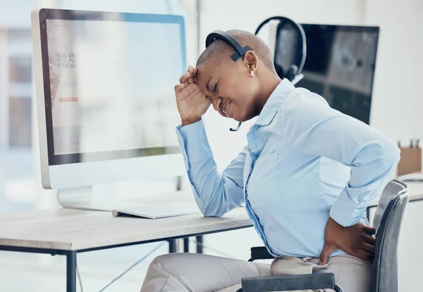 Black woman, backache and stress in call center with consultant suffering pain, muscle or spinal injury at her desk. Back, pain and burnout by crm manager with headache and posture problem in office.