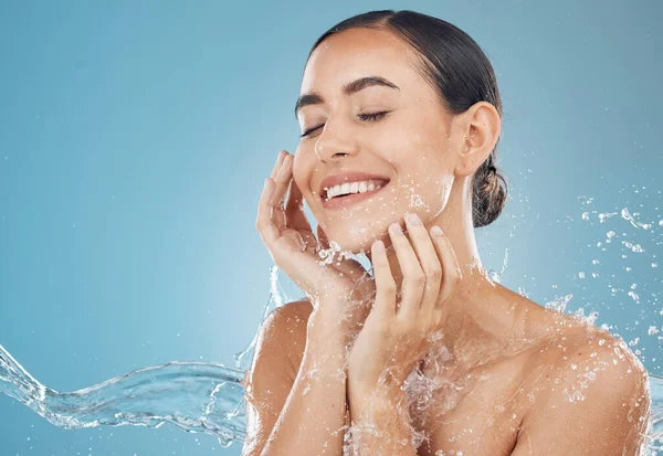 Beauty, skincare and splash of water with woman for wellness, hydration and fresh spa. Relax, smile and health with girl against blue background with mock up for luxury, natural cosmetics and shower.