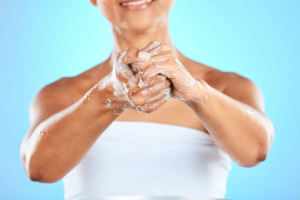Hands, cleaning and woman washing hands in studio for health, hygiene and safety from bacteria against blue background. Hand, wellness and germ prevention by model with soap, bubble and foam product.
