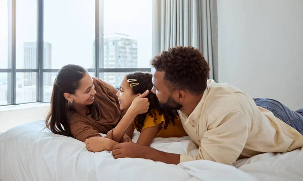 Happy family, relax and girl in bed with mother and father, bond and resting in their home together. Love, black family and child enjoy lazy morning indoors with parents, rest and embrace in bedroom.