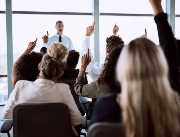 stock image Sometimes a little more clarification is needed. a group of businesspeople raising their hands to ask questions during a conference