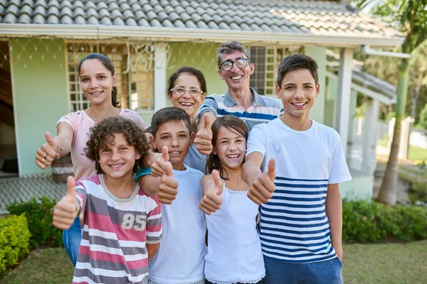 質問が何であれ 家族は常に答えです 彼らの裏庭に一緒に立って親指を放棄する幸せな多世代の家族の肖像画 — ストック写真