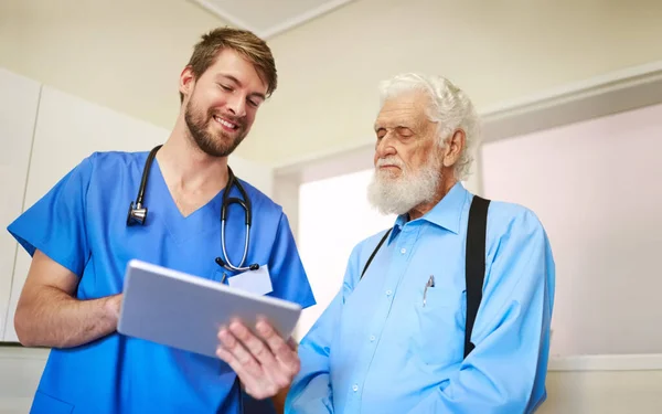 Let me walk you through my treatment plan. a young doctor explaining a diagnosis to his senior patient by using a tablet