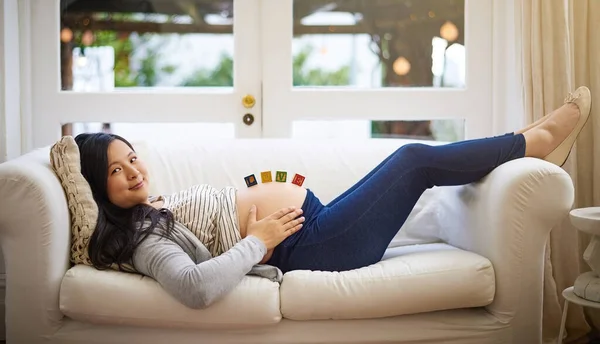 I get a little more excited each day..Cropped portrait of an attractive young pregnant woman relaxing on the sofa at home
