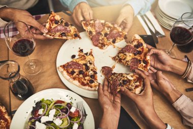 Yemek hazır. Bir grup tanınmayan insanın yüksek açılı görüntüsü. Her biri bir restoranda otururken bir dilim pizza alıyor.