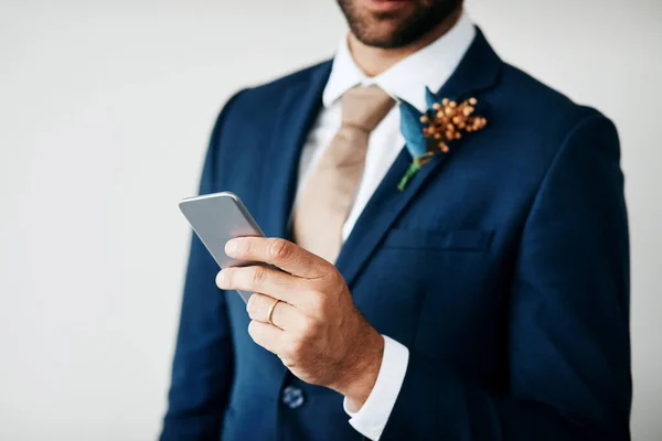 stock image I need to take a selfie of this moment. Cropped studio shot of a stylish young groom holding a cellphone while standing against a gray background
