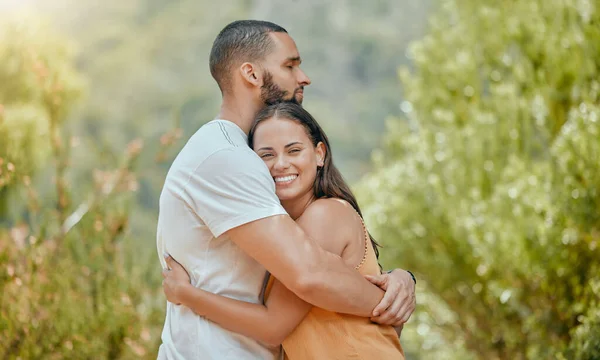 stock image Love, hug and couple on a date in nature, happy and at peace together during summer. Relax, smile and young man and woman hugging with affection and bonding in a park or garden on a holiday.