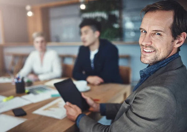 stock image I never enter a meeting without it. Portrait of a mature businessman using a digital tablet while in a meeting in an office