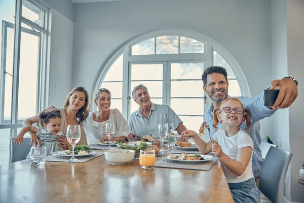 Grandparents, parents and children taking a selfie at dinner, eating meal together on weekend. Big family, love and dad holding smartphone for picture enjoying lunch, supper and holiday celebration.