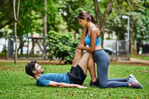 让我帮你伸出手来一对年轻的运动型夫妇在户外一起锻炼时伸展身体 — 图库照片