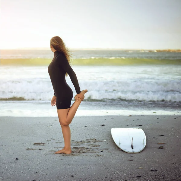 サーフィンの前にストレッチ ビーチで暖まる認識できない若い女性サーファーの完全な長さのショット — ストック写真