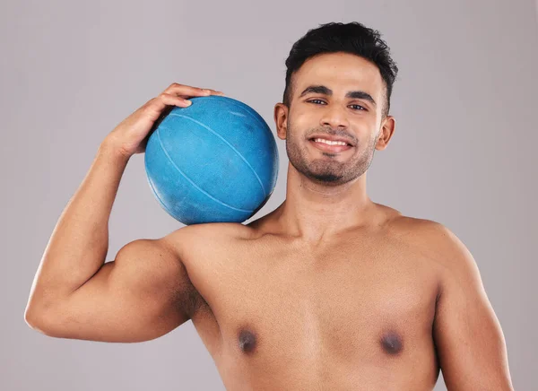 Health, fitness and medicine ball with a man athlete in studio on a gray background for exercise or training. Gym, wellness and workout with an athletic or strong male posing with sports equipment.