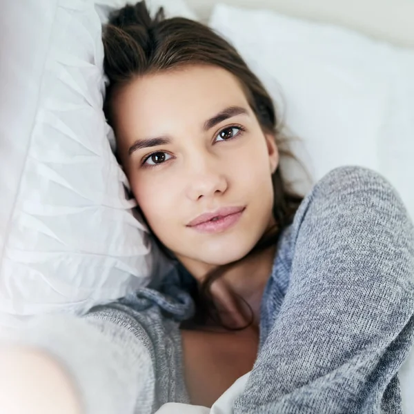 stock image This is me. Portrait of an attractive young woman taking a self portrait with her cellphone while lying in bed at home