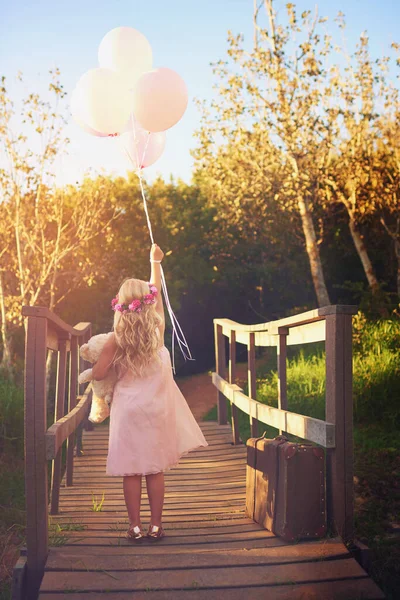 アップ アップ そして離れて 橋の真ん中に立っている間に風船とテディベアを持った無名の少女が — ストック写真