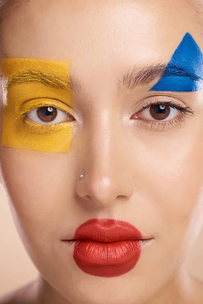 Beauty, art and portrait of woman paint on face, creative makeup and self expression. Skincare, creativity and color block shape cosmetics, empowerment and freedom to express for young beautiful girl.