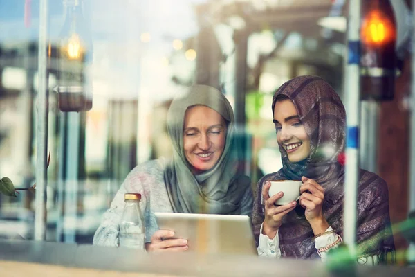 和朋友一起跟上社交媒体的潮流 两个女人在咖啡店一起使用数码平板电脑 — 图库照片