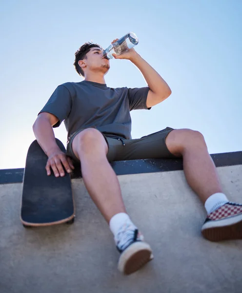 スケートボード 若い男と飲料水ボトル リラックスして晴れた日の屋外で休憩 スケート選手や水和物 喉の渇きと健康のためのスポーツ 健康と夏に楽しみを持っています — ストック写真
