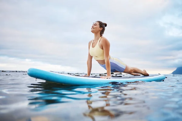 サーフィン 女性は午前中にサーフボードでヨガをし サーフィンとリラックスする準備ができています 海のパドルでストレッチをするウェルネス ウォータースポーツ 女の子は 自然の中で穏やかな波と平和をお楽しみください — ストック写真