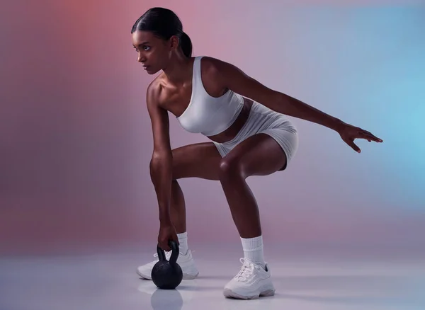 stock image Fitness, kettlebell and woman training in studio for full body balance, powerful muscles and strong arms. Sports, exercise and healthy Indian girl swinging weights or weightlifting in a squat pose.