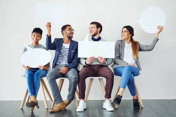 stock image We not keeping our opinions to ourselves. a diverse group of creative employees holding up speech bubbles inside