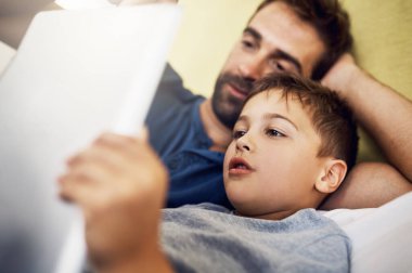 Bir tane daha okuyalım baba. Genç bir adam oğluyla birlikte dijital tablet kullanıyor.
