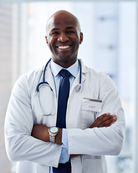He is the professional of all professionals. Portrait of a cheerful young doctor standing with his arms folded inside of a hospital during the day