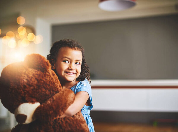 This one is my favorite toy. Portrait of a little girl holding her teddy bear at home