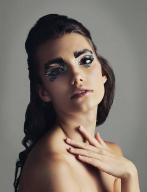 Yaratıcılığını ifade etmek için makyaj yap. Göz makyajı yapan çekici bir genç kadının stüdyo fotoğrafı.