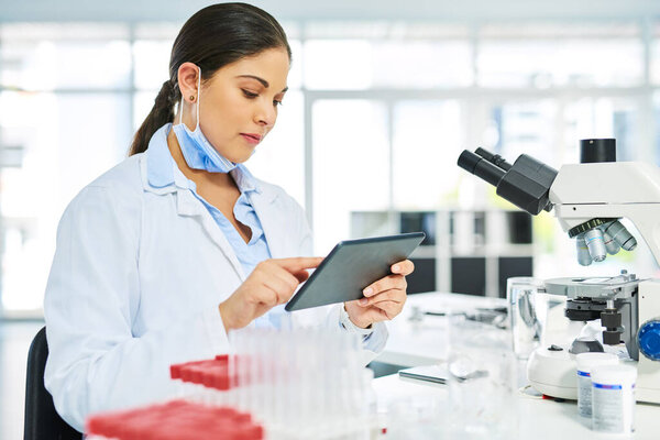 She saves all her theories on her handy device. a young scientist using a digital tablet in a lab