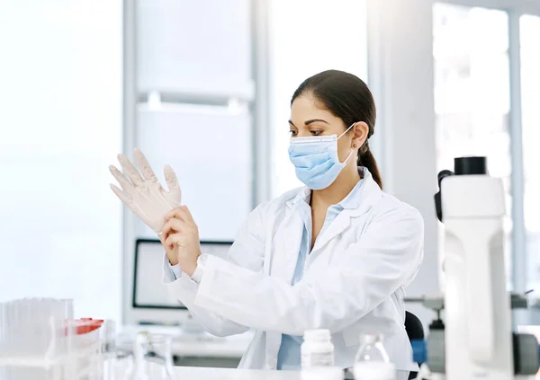 stock image Lets get experimenting. a young scientist putting on surgical gloves while working in a lab