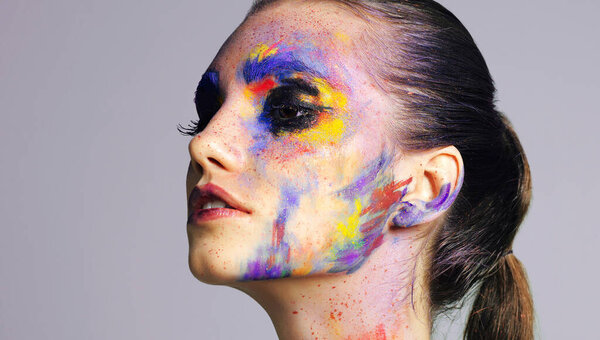Uniqueness is beautiful. Studio shot of an attractive young woman with brightly colored makeup against a purple background