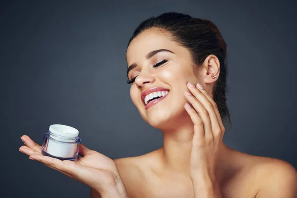 stock image What a magical tub of skincare miracles. Studio shot of a beautiful young woman with flawless skin posing with moisturizer against a blue background