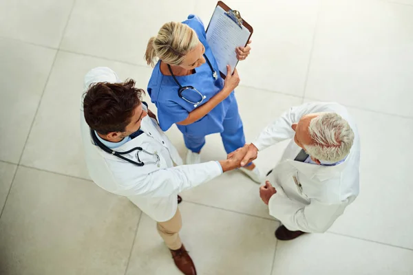 stock image Bringing in an expert opinion. High angle shot of a team of doctors shaking hands in the hospital