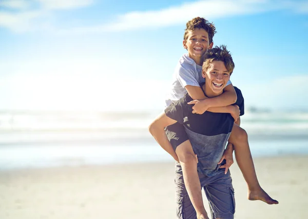 兄と親友 幸せな少年の肖像画彼の弟にビーチでピギーバックに乗る — ストック写真