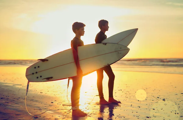 两个年轻的海洋狂热者两个弟弟举着冲浪板向大海望去 — 图库照片