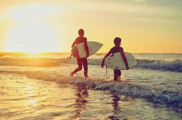 Wyjeżdżam Fale Dwóch Młodych Braci Niosących Deski Surfingowe Podczas Brodzenia — Zdjęcie stockowe