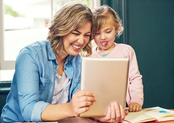 学習は楽しく教育的なものです 明るい若い母親と幼い娘が自宅のデジタルタブレットで遊んでいます — ストック写真