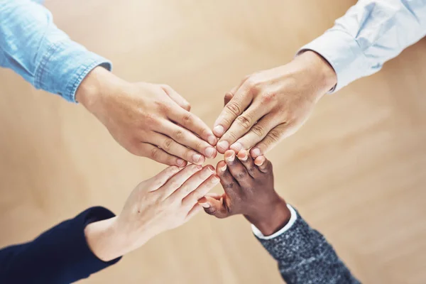 Work as one, get it done. High angle shot of a group of unidentifiable businesspeople joining their hands together in unity