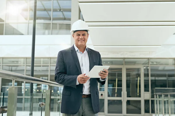 This is where the project begins. Portrait of a cheerful professional male architect holding a digital tablet while looking at the camera inside of a building