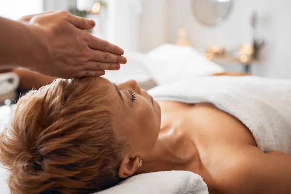 Spa, black woman and head massage to relax, peaceful and calm for clear mind, wellness and stress relief on table. Senior female, physical therapy and luxury vacation for health, body care and fresh