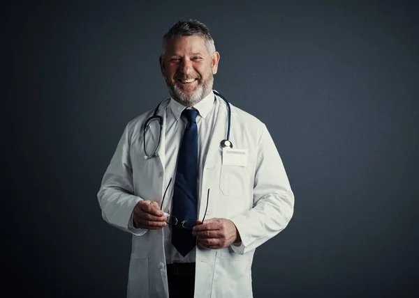 Saving lives gives me purpose. Studio portrait of a handsome mature male doctor standing against a dark background