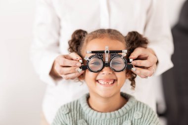 Görüş, optometrist ve gözlüklü çocuk portresi test edilecek, kontrol edilecek ve incelenecek. Göz muayenesi, optik tanı ve muayene için doktor muayenehanesinde bulunan sağlık, tıbbi ve genç kız.