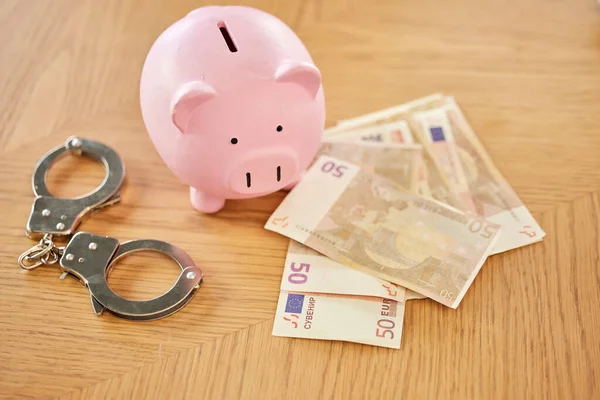 Piggy bank, money and handcuffs fraud crime for euro scam, corruption and criminal wealth exchange. Economy crisis, bankruptcy and illegal euros for taxes bribe or bank dollars payment offer